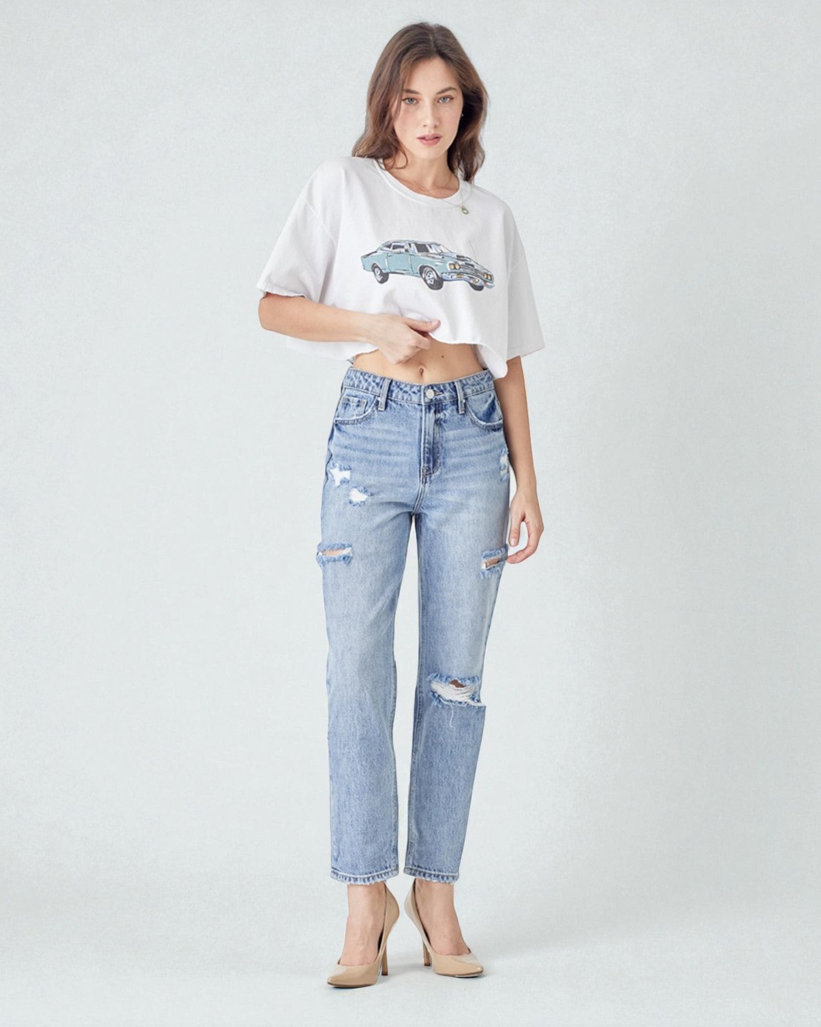 Woman wearing a white oversized t-shirt and light blue ripped jeans on a white background