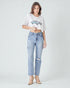 Woman wearing a white oversized t-shirt and light blue ripped jeans on a white background
