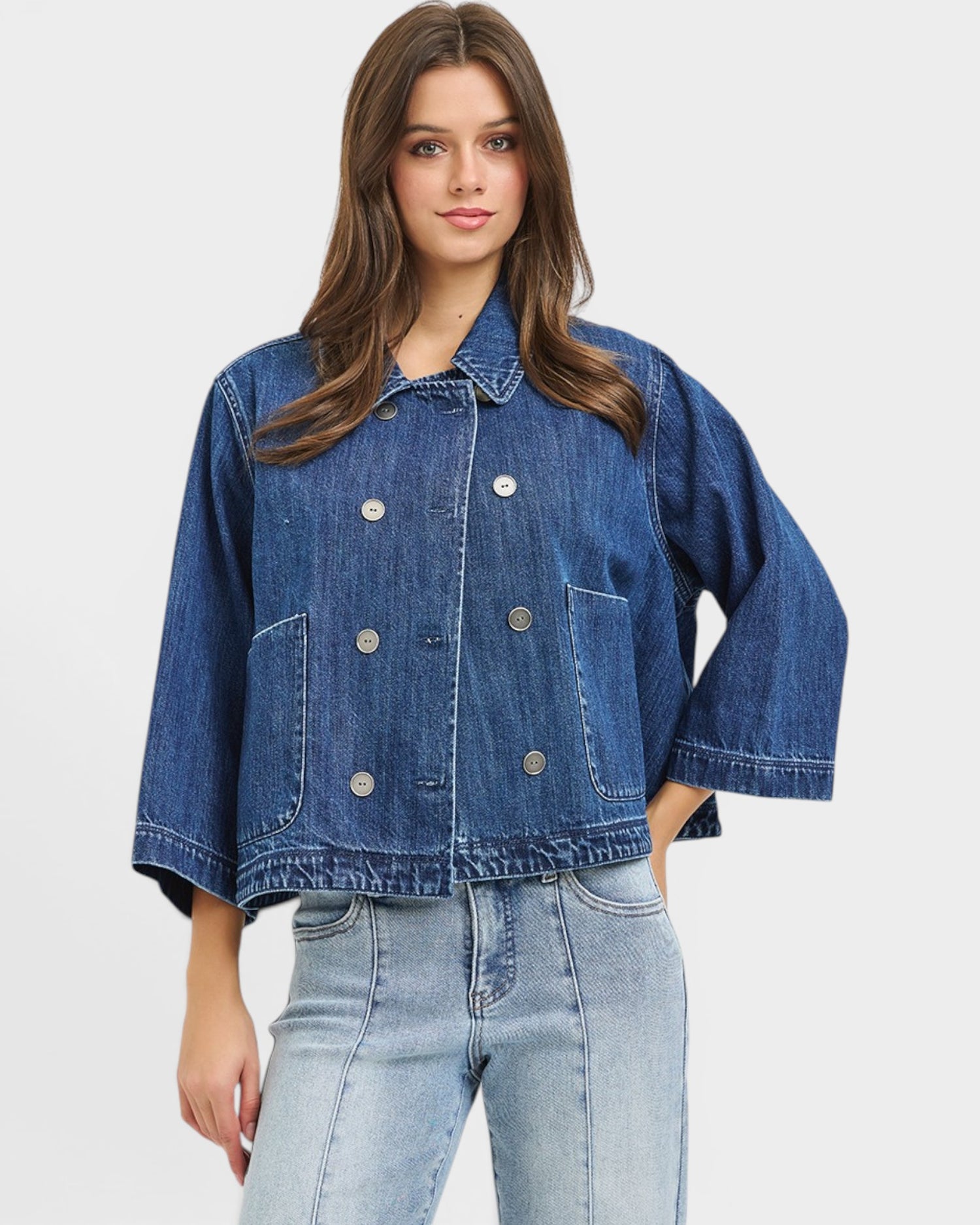 Woman wearing a blue denim jacket on a plain background
