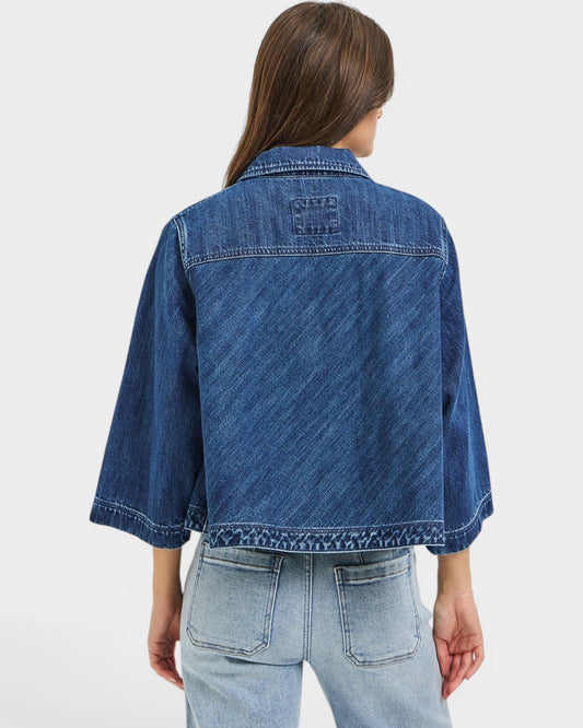 Person wearing a blue denim jacket on a light gray background