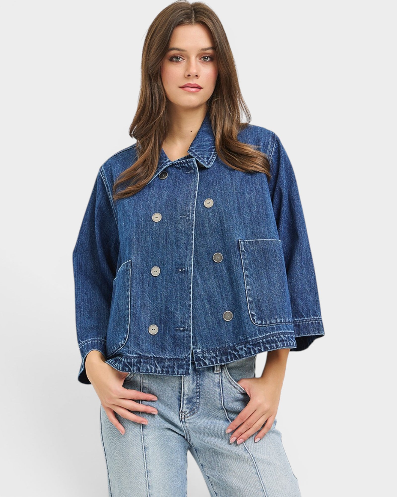 Woman wearing a blue denim jacket and jeans on a white background
