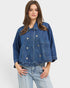 Woman wearing a blue denim jacket and jeans on a white background