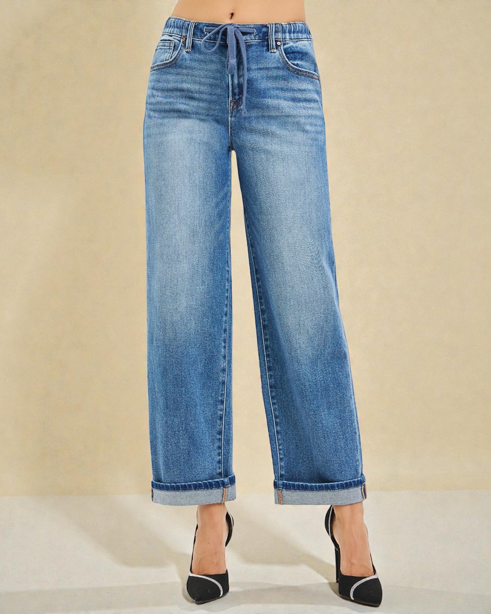 Blue jeans worn by a person on a beige background