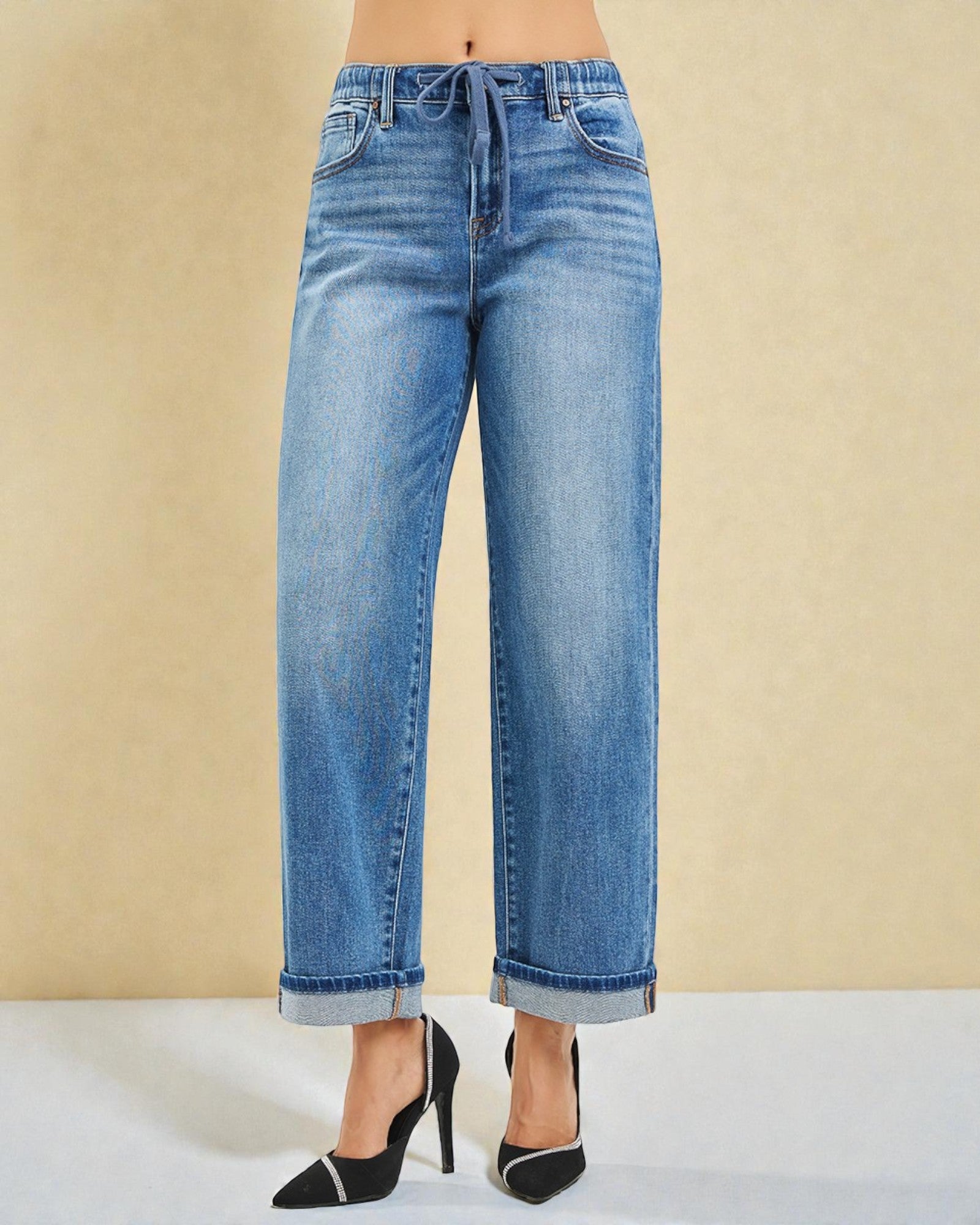 Blue jeans worn by a person on a beige background