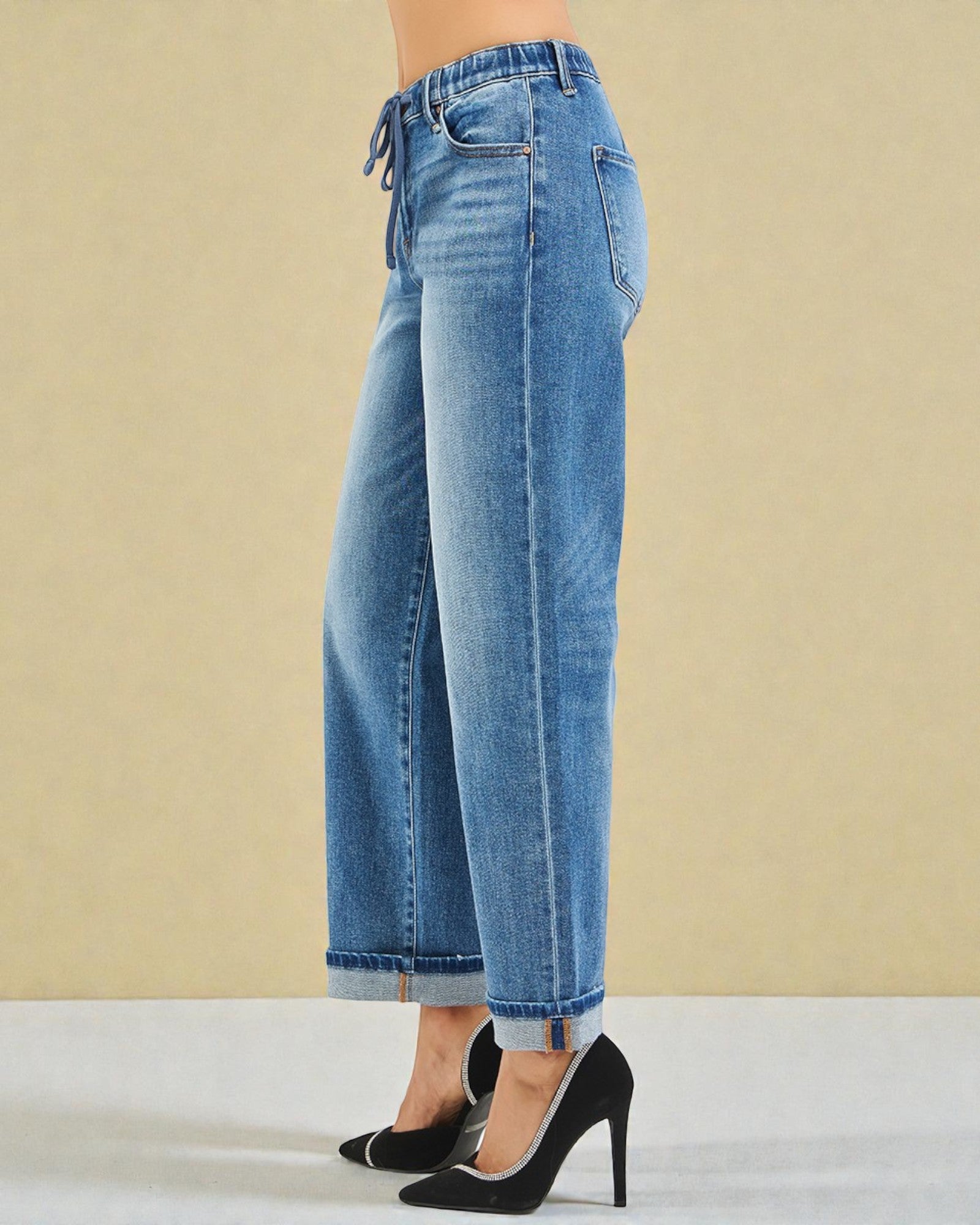 Blue jeans worn by a person on a beige background