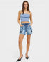 Woman wearing a light blue crop top and denim shorts with star patterns on a white background