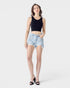 Woman wearing a black tank top and light blue denim shorts on a white background