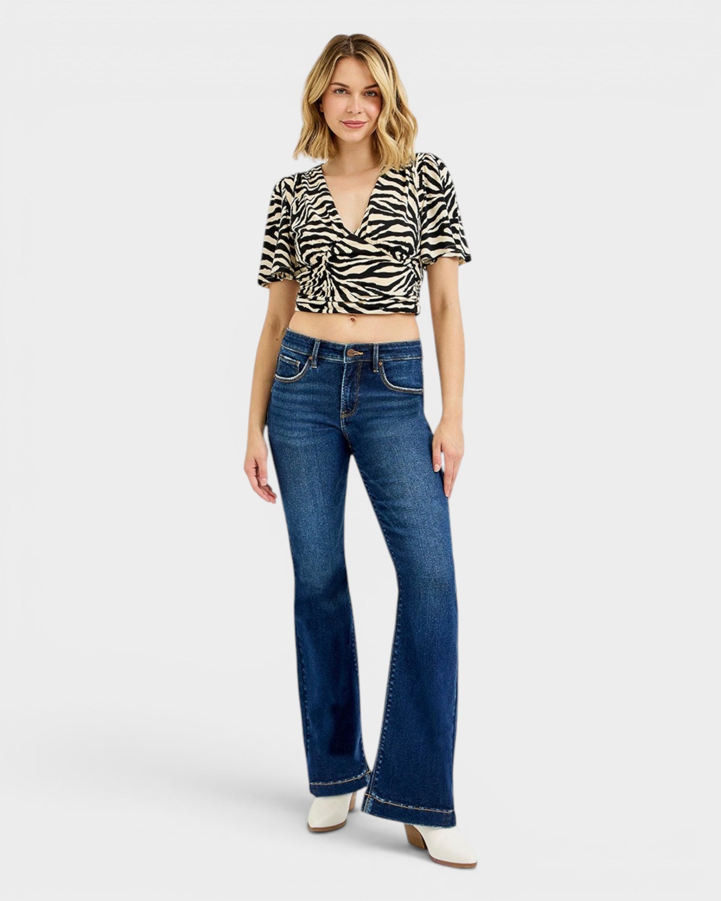 Woman wearing a zebra print top and blue jeans on a white background