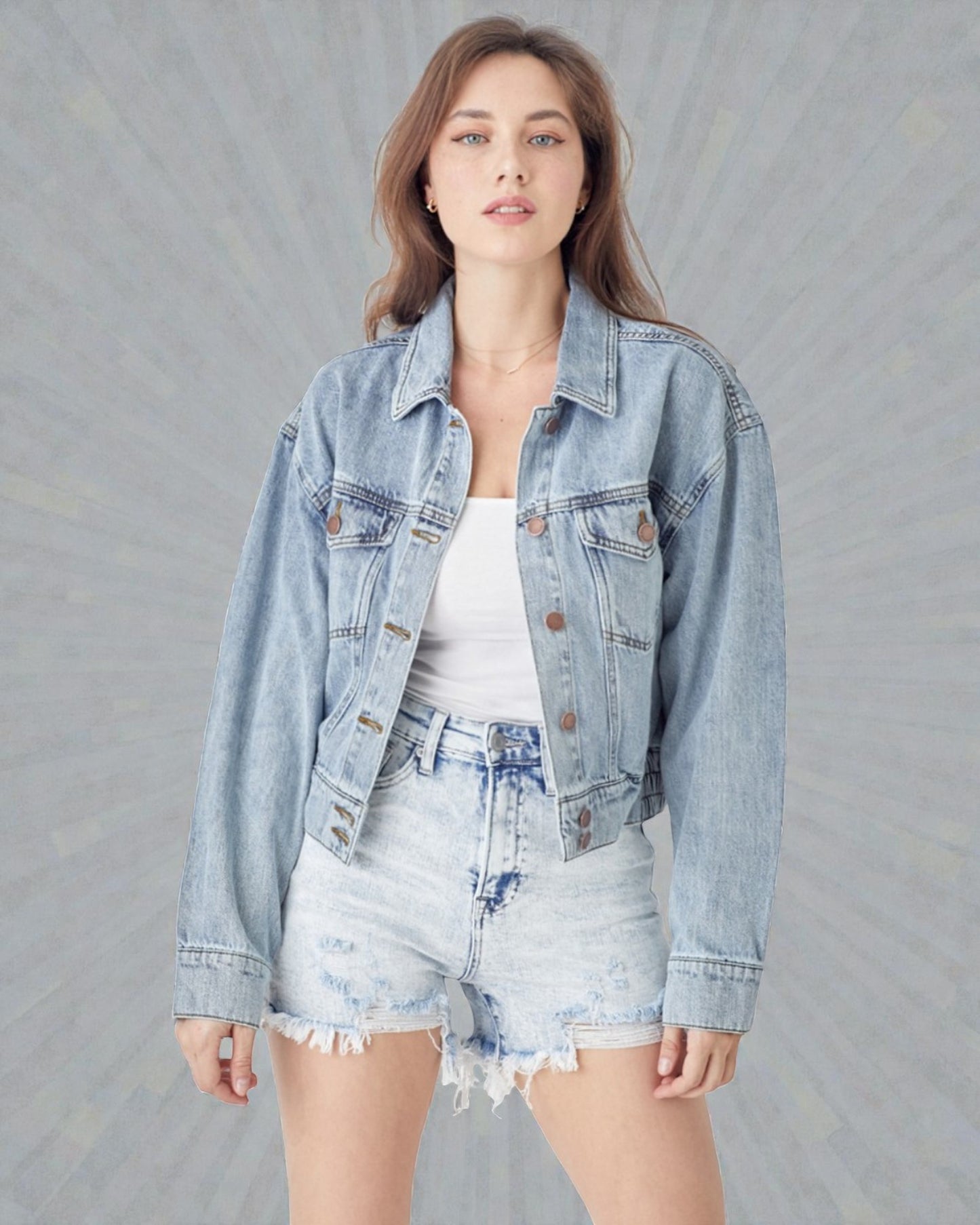 Woman wearing a light blue denim jacket and shorts on a gray background