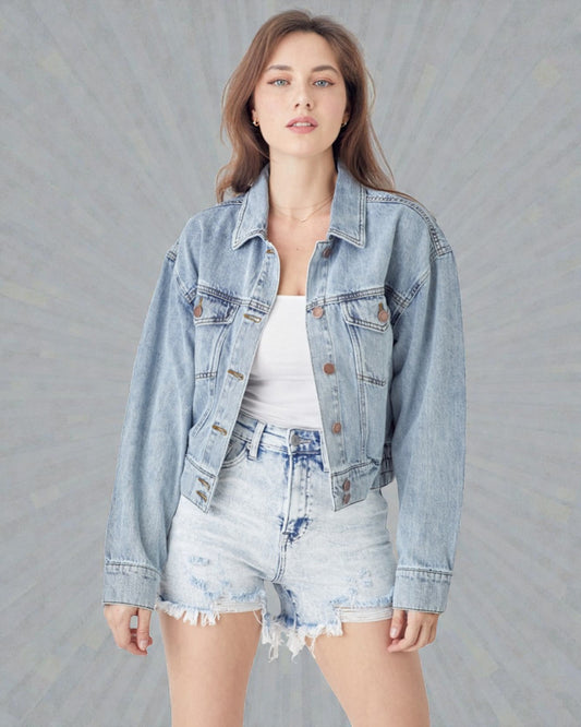 Woman wearing a light blue denim jacket and shorts on a gray background