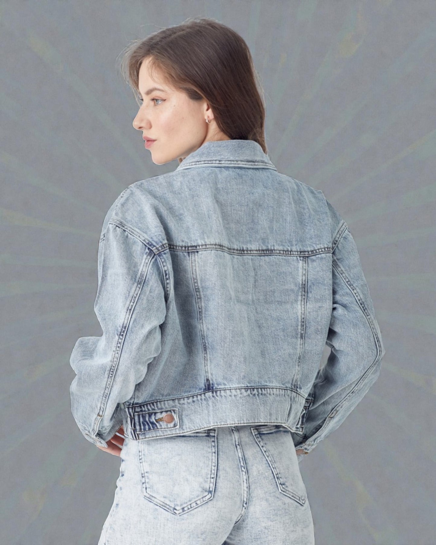 Woman wearing a light blue denim jacket against a gray background
