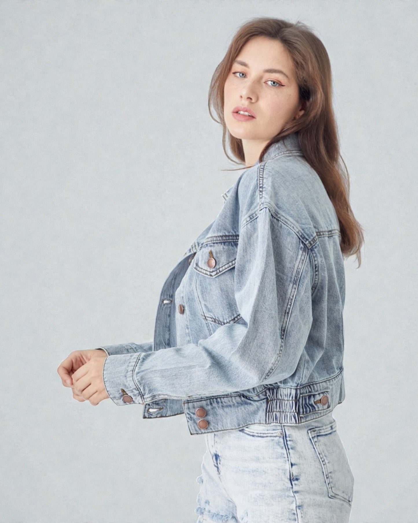 Woman wearing a light blue denim jacket on a plain background
