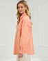 Woman wearing a peach-colored jacket against a white background