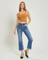 Woman wearing a mustard yellow top and blue jeans on a white background