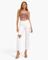 A model wearing a dusty rose ribbed crop top with button details and white cropped jeans with a distressed knee cutout, paired with clear high-heeled sandals, against a light gray studio background.