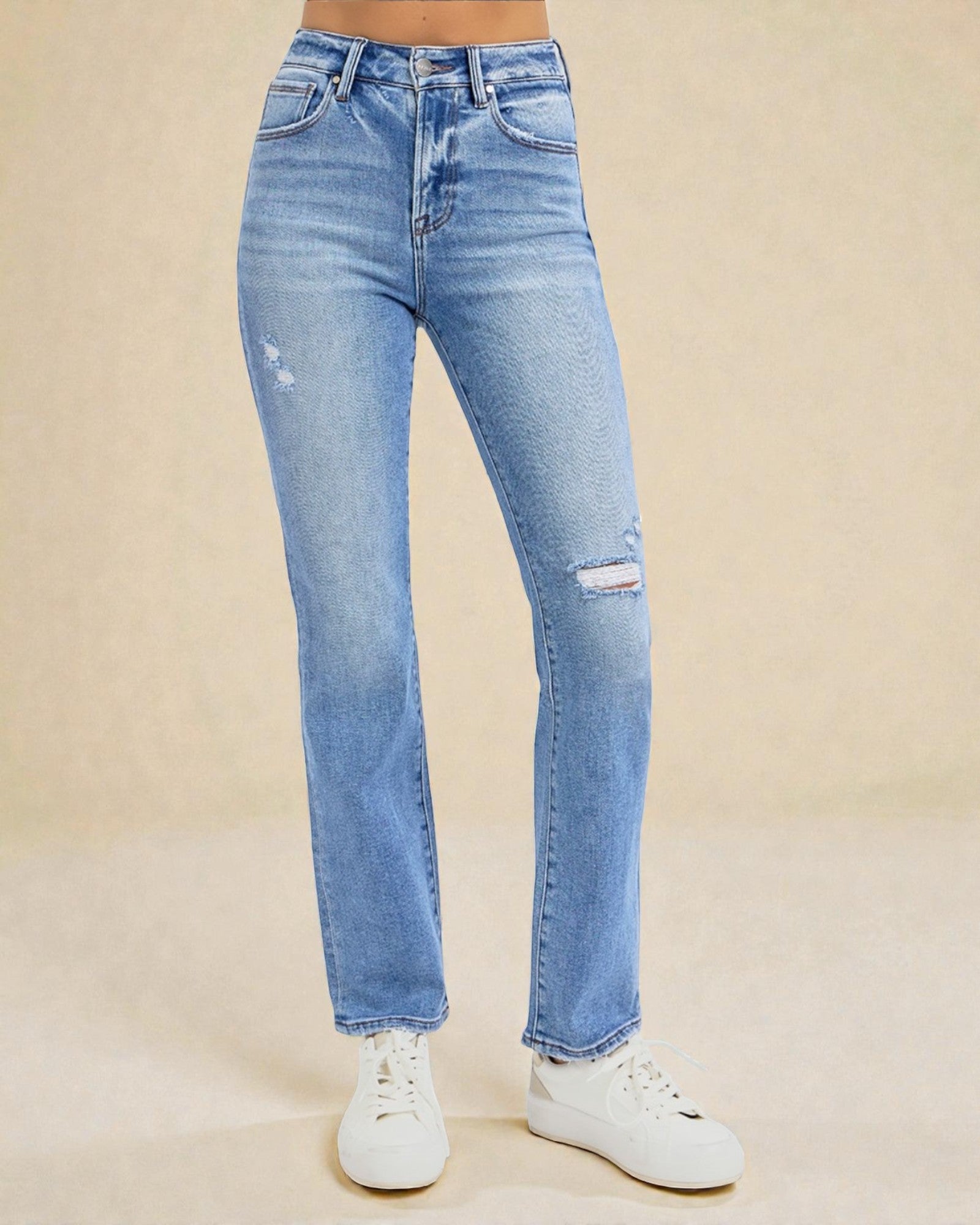 Light blue jeans with slight distressing on a beige background