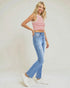 Woman wearing a red and white striped crop top and blue jeans on a plain background