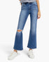 A model wearing a pair of medium-wash blue denim jeans with a distressed knee cutout and a flared leg, paired with white sneakers against a plain white background.