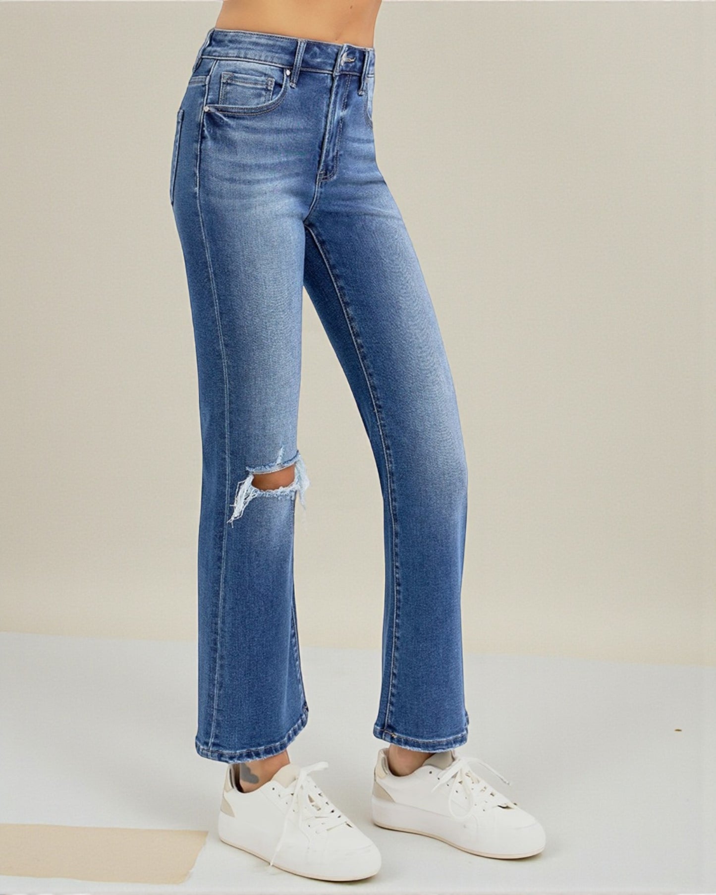 Blue jeans with a slight distressed look worn by a person on a neutral background