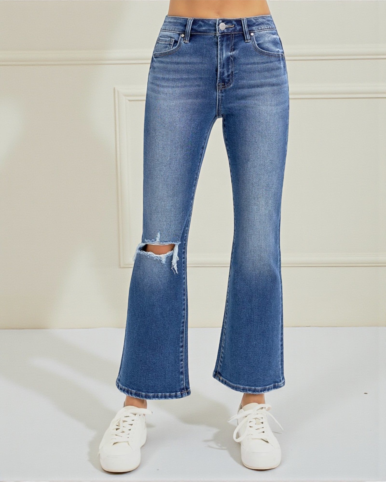 Blue jeans with a distressed knee on a white background
