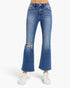 A person wearing medium-wash blue denim flare jeans with a distressed rip at the knees and white sneakers, shown against a plain light gray studio background.