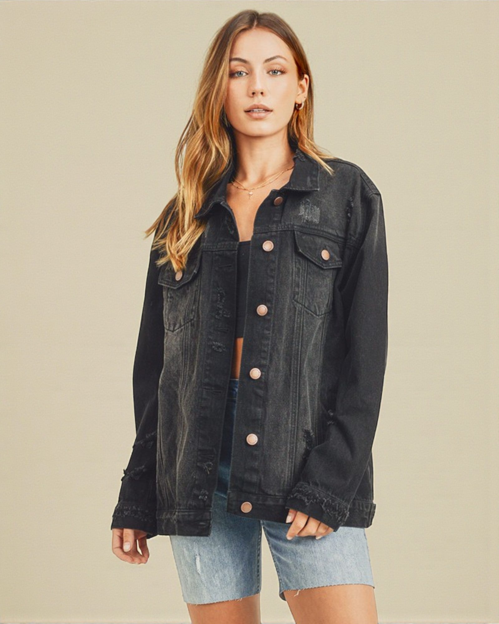 Woman wearing a black denim jacket on a beige background