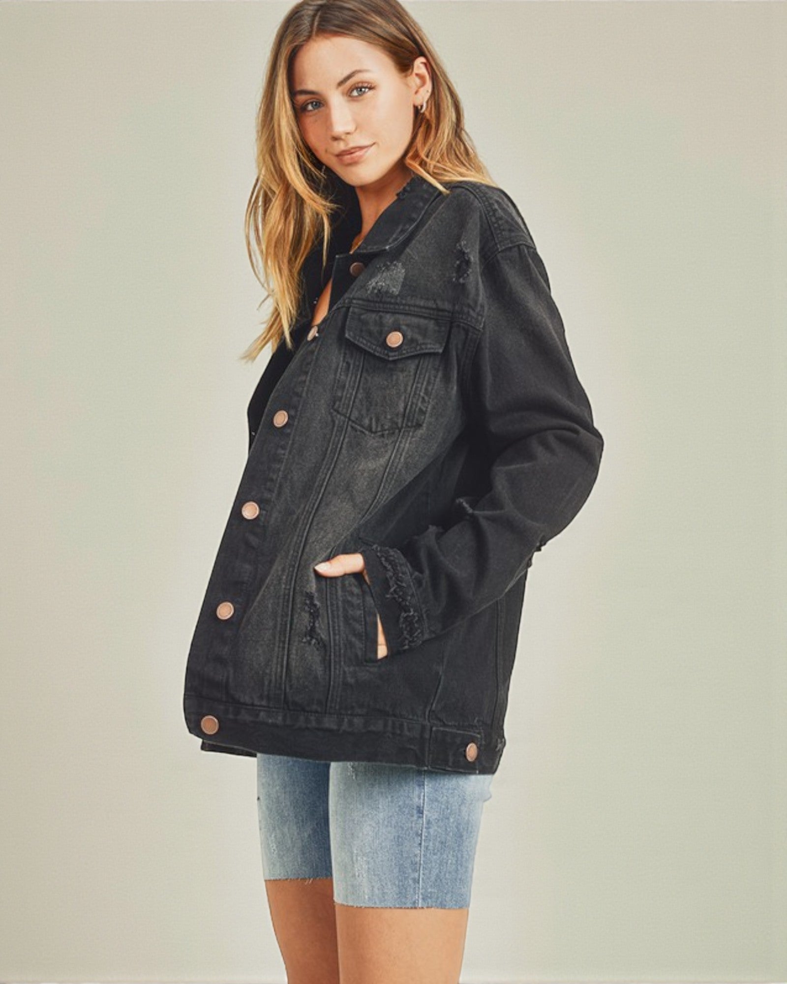 Woman wearing a black denim jacket on a plain background