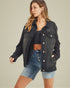 Woman wearing a black denim jacket and blue shorts on a beige background