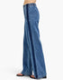 A side view of a person wearing wide-leg blue denim jeans with a dark blue vertical stripe detail down the side, paired with black flat sandals, against a plain white background.