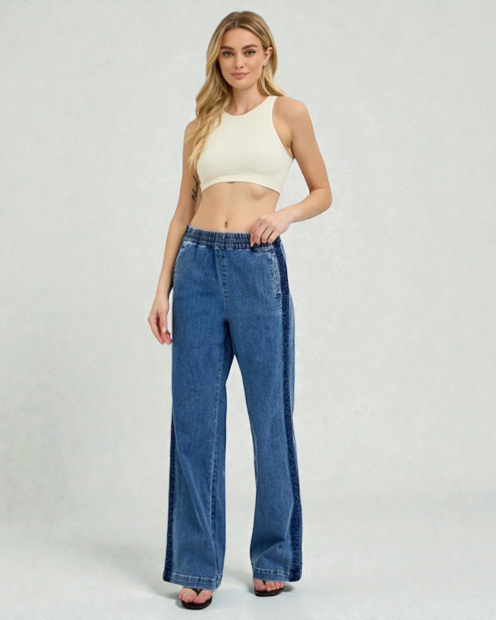 Woman wearing blue jeans and a white top on a plain background