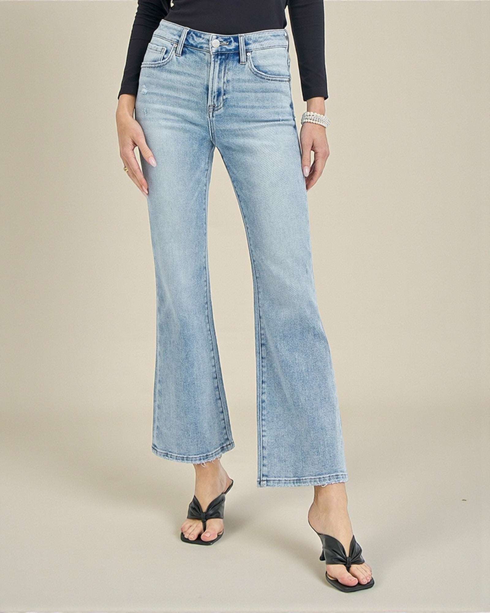 Light blue flared jeans worn by a person on a beige background