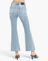 Light wash blue flare jeans shown from the back on a model, paired with black heeled mule sandals against a plain white studio background.