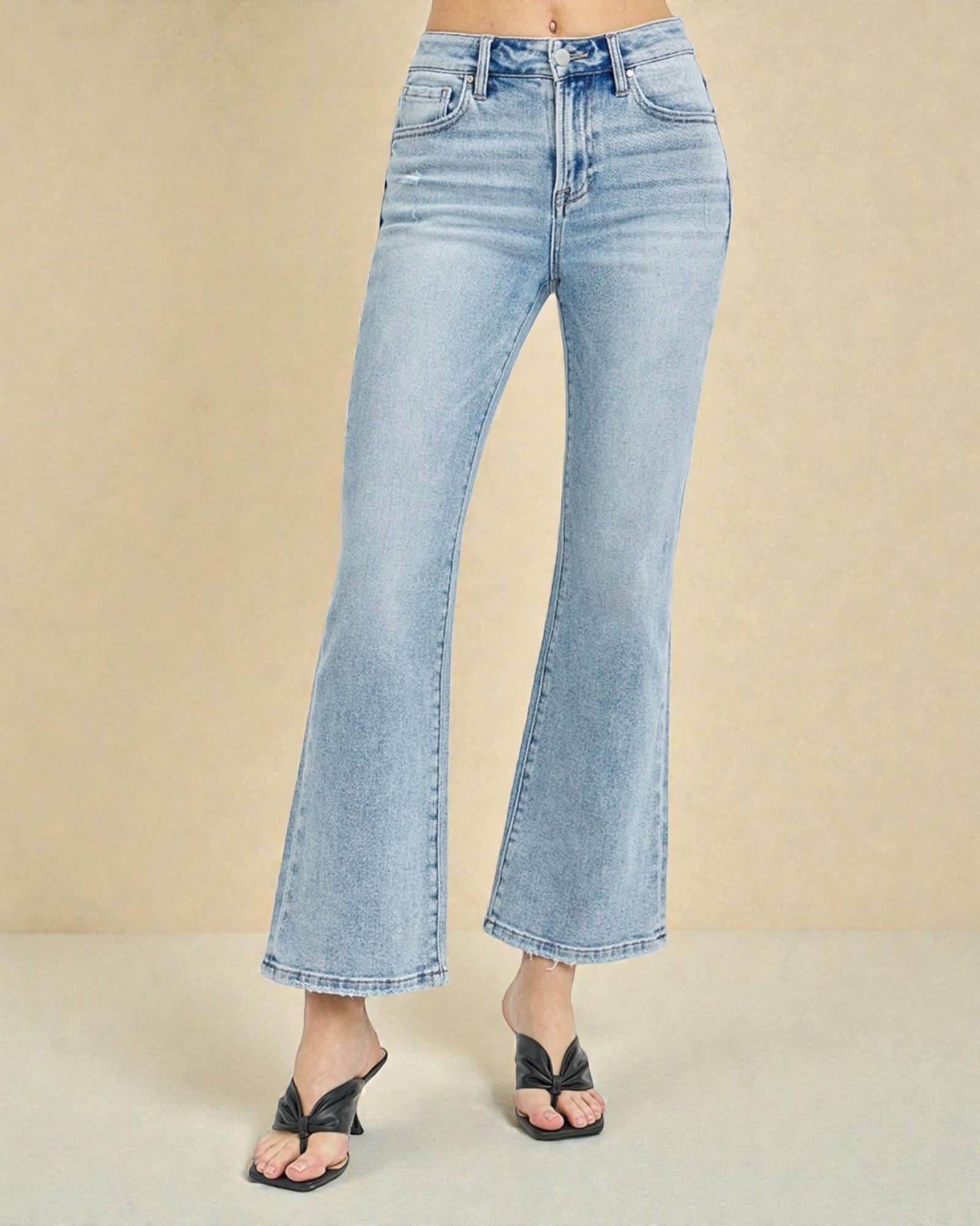 Light blue flared jeans worn by a person on a beige background