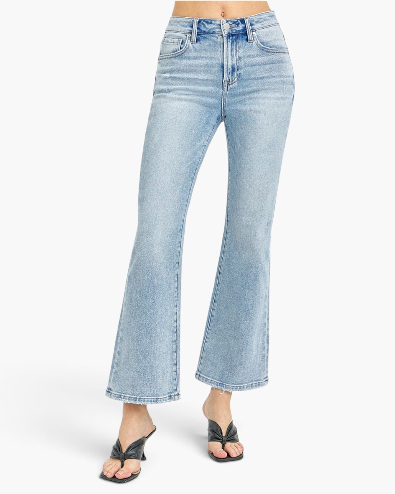 Light-wash blue denim flare jeans shown on a model from the waist down, paired with black slide sandals against a plain white studio background.