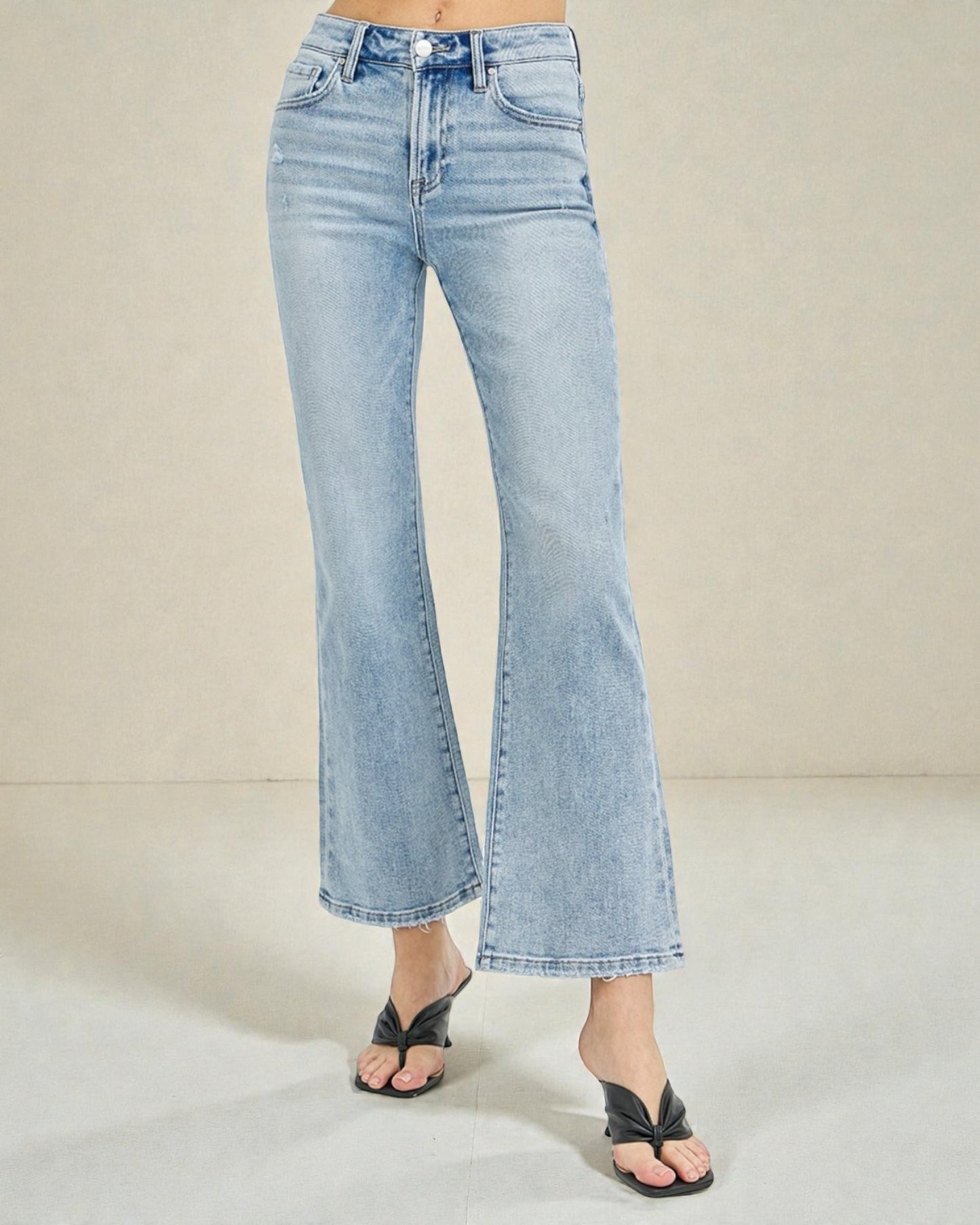 Light blue flared jeans worn by a person on a neutral background