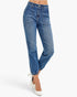 A model wearing medium-wash blue denim jeans with a straight-leg fit, cuffed hems, and front patch pockets, paired with white pointed-toe heels against a light gray studio background.