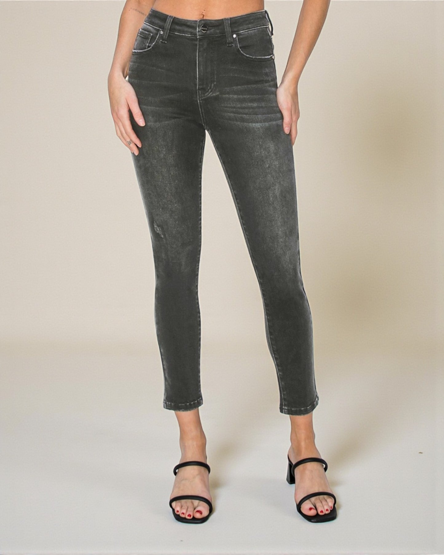 Person wearing black distressed jeans on a plain background