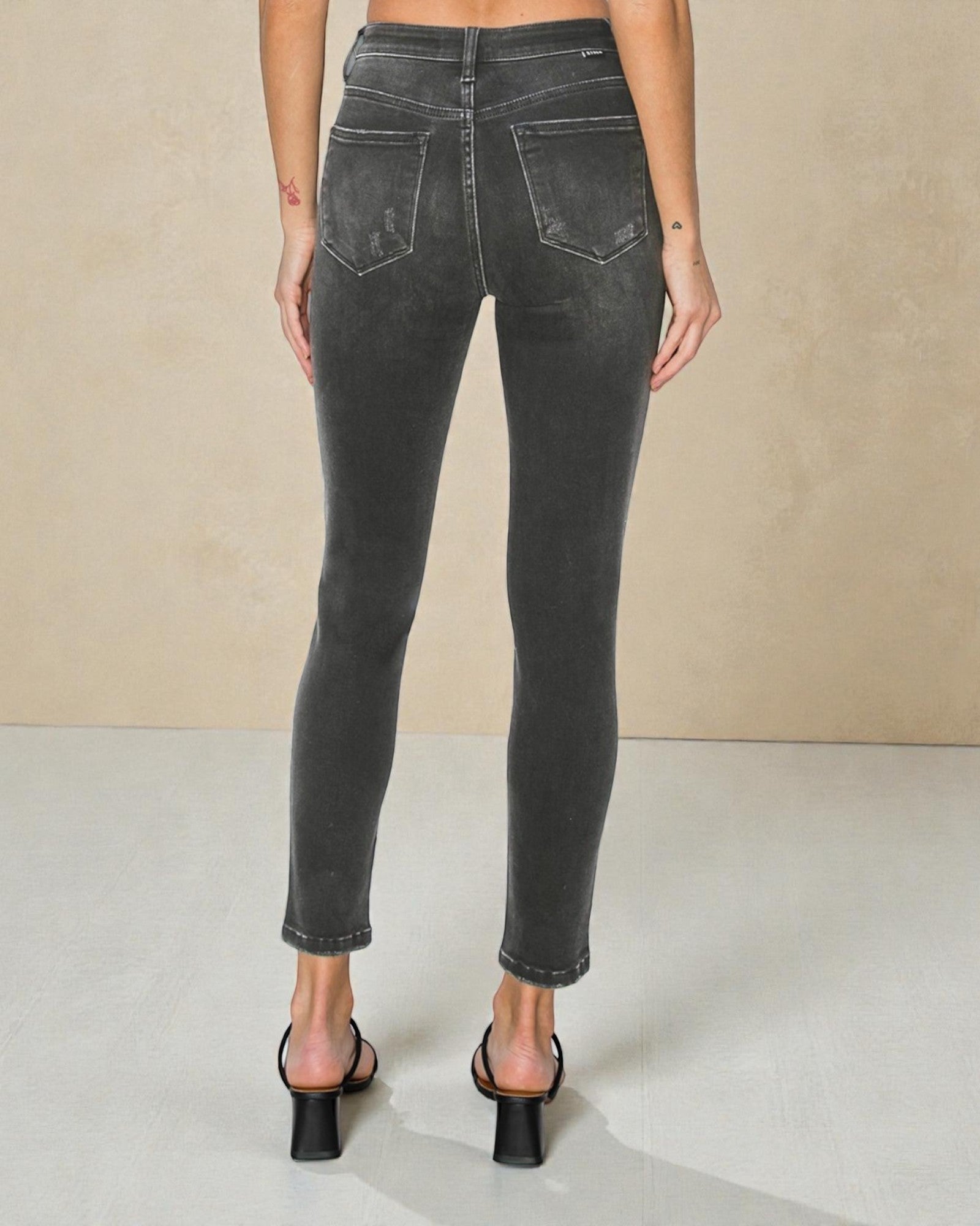 Person wearing black jeans on a neutral background