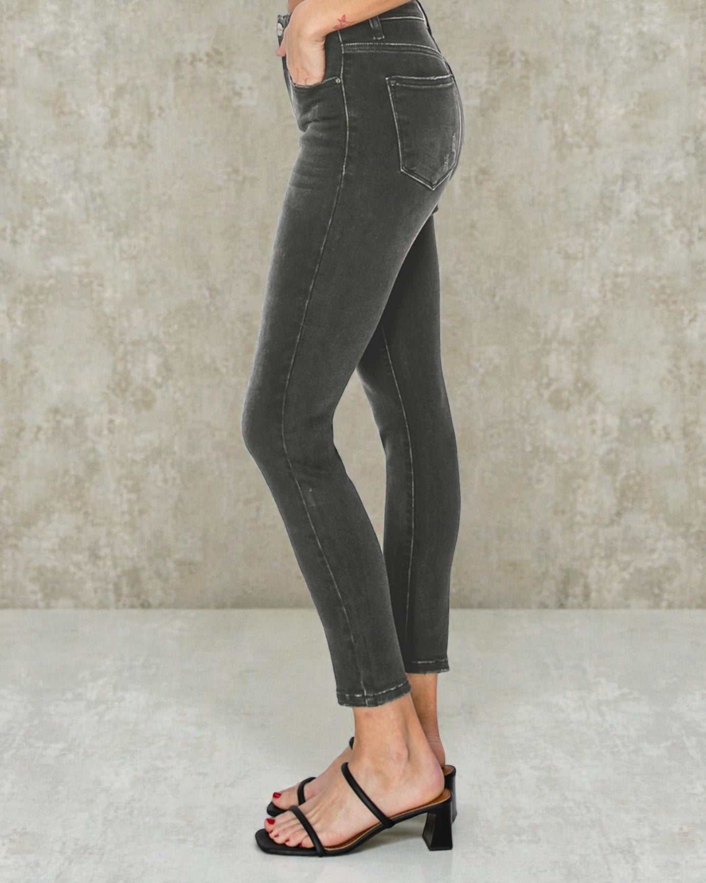 Person wearing black jeans against a neutral background