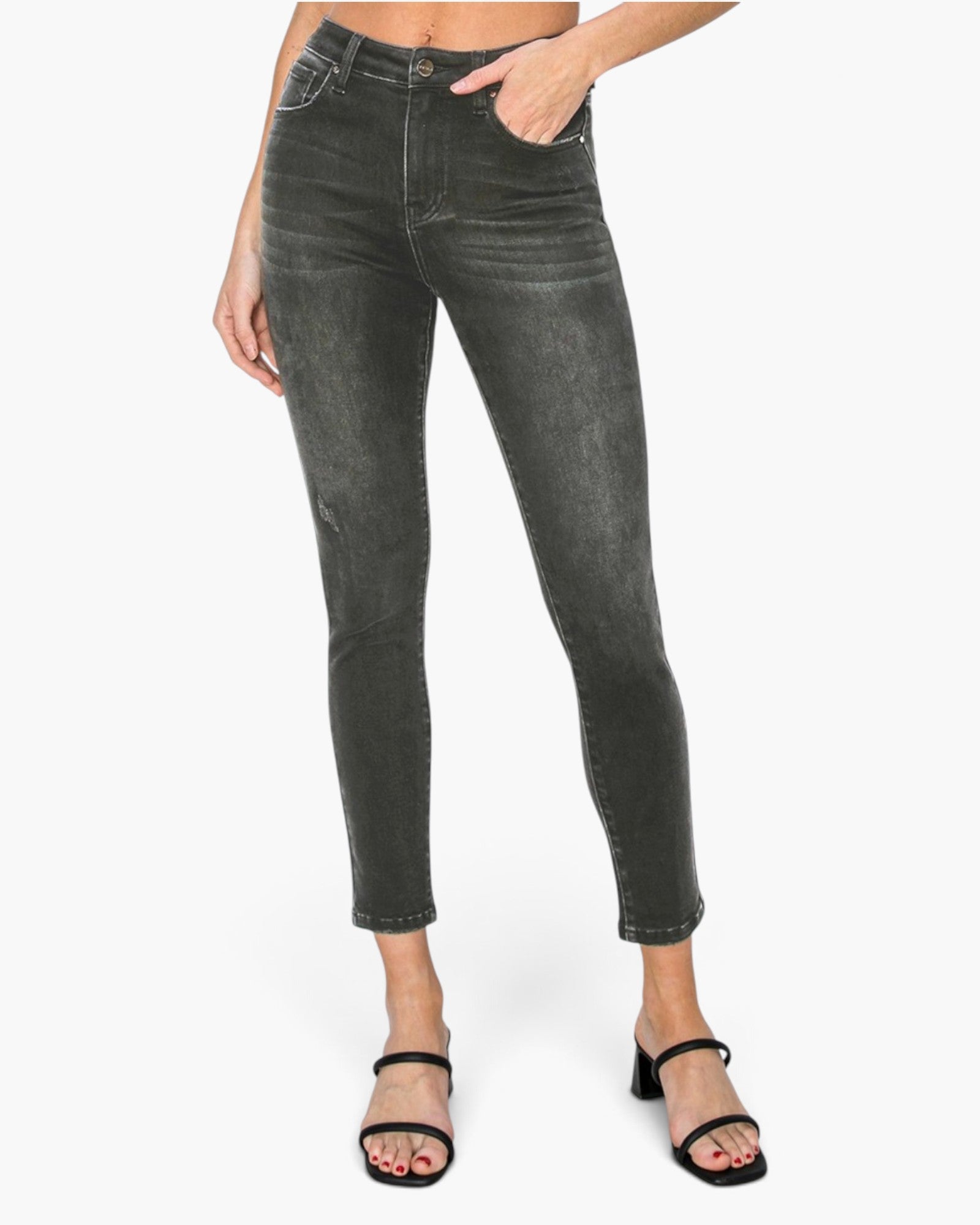 A model wearing dark gray slim-fit ankle-length jeans with a faded wash, paired with black heeled sandals, shown against a plain white studio background.