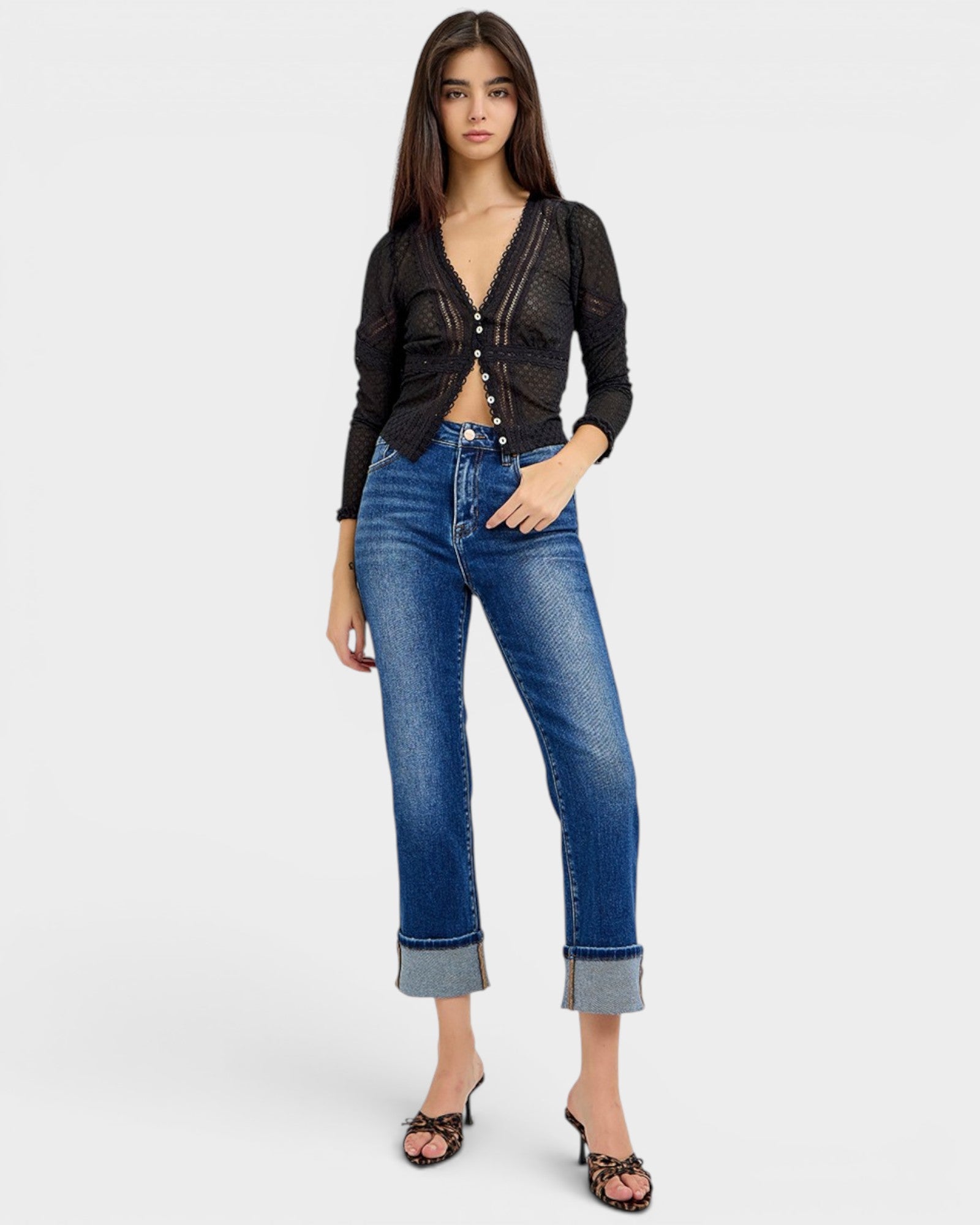 Woman wearing a black cropped jacket and blue jeans on a white background