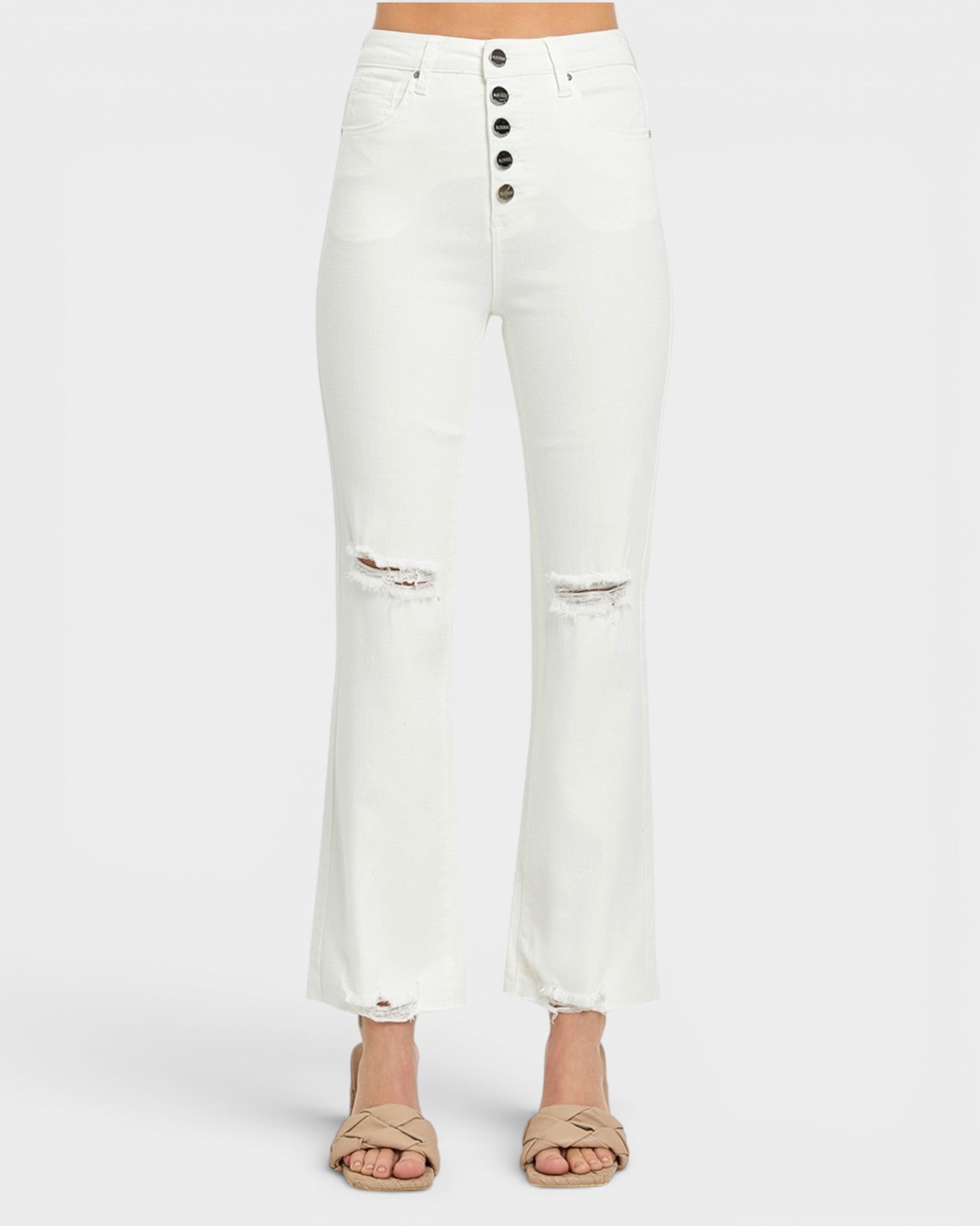 White high-waisted cropped flare jeans with a five-button closure and distressed knee details, shown on a model wearing beige sandals against a light gray background.
