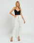 Woman wearing a black crop top and white jeans on a white background