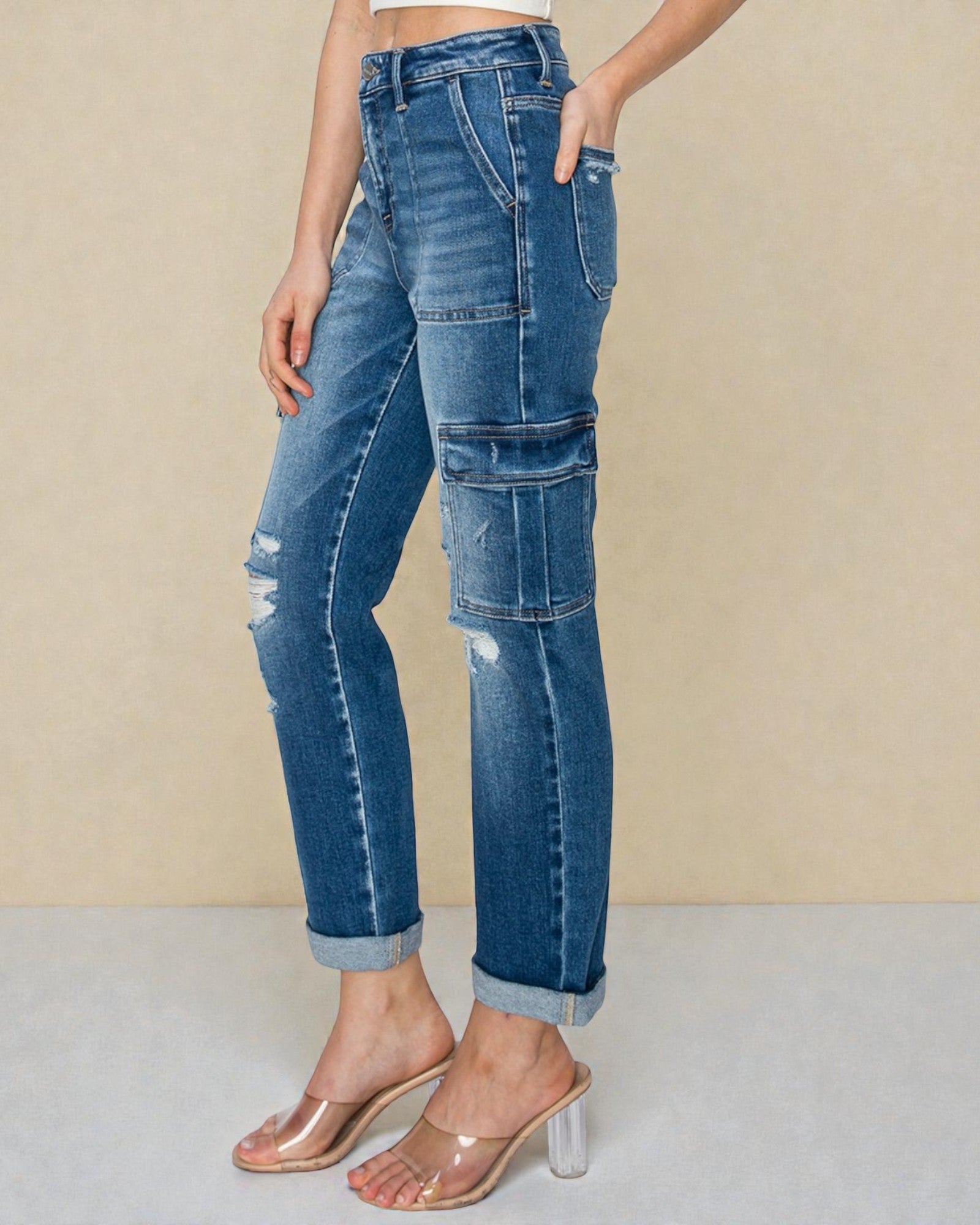 Person wearing blue jeans with patchwork design on a beige background