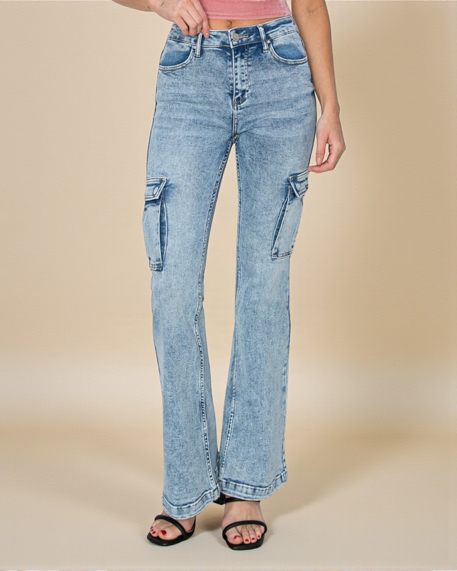 Light blue flared jeans worn by a person on a beige background