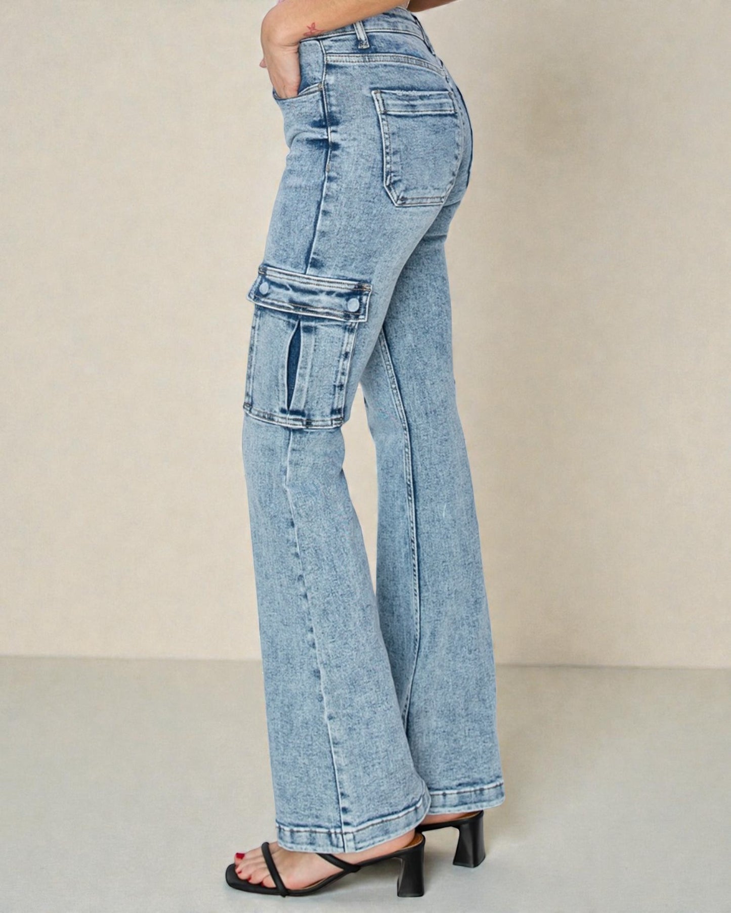 Light blue flared jeans worn by a person on a beige background