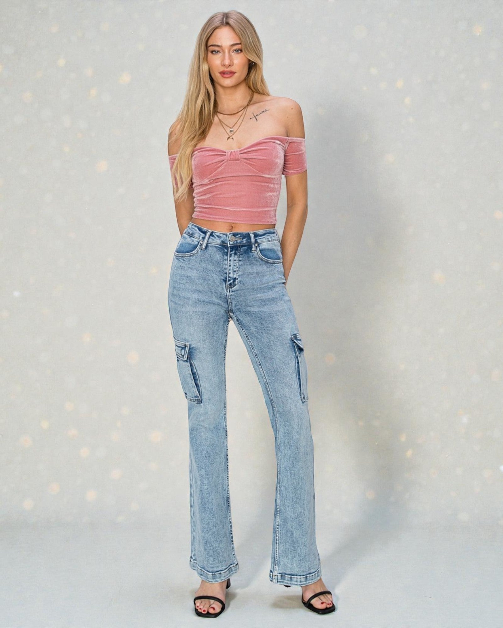 Woman wearing a pink top and blue jeans against a light gray background