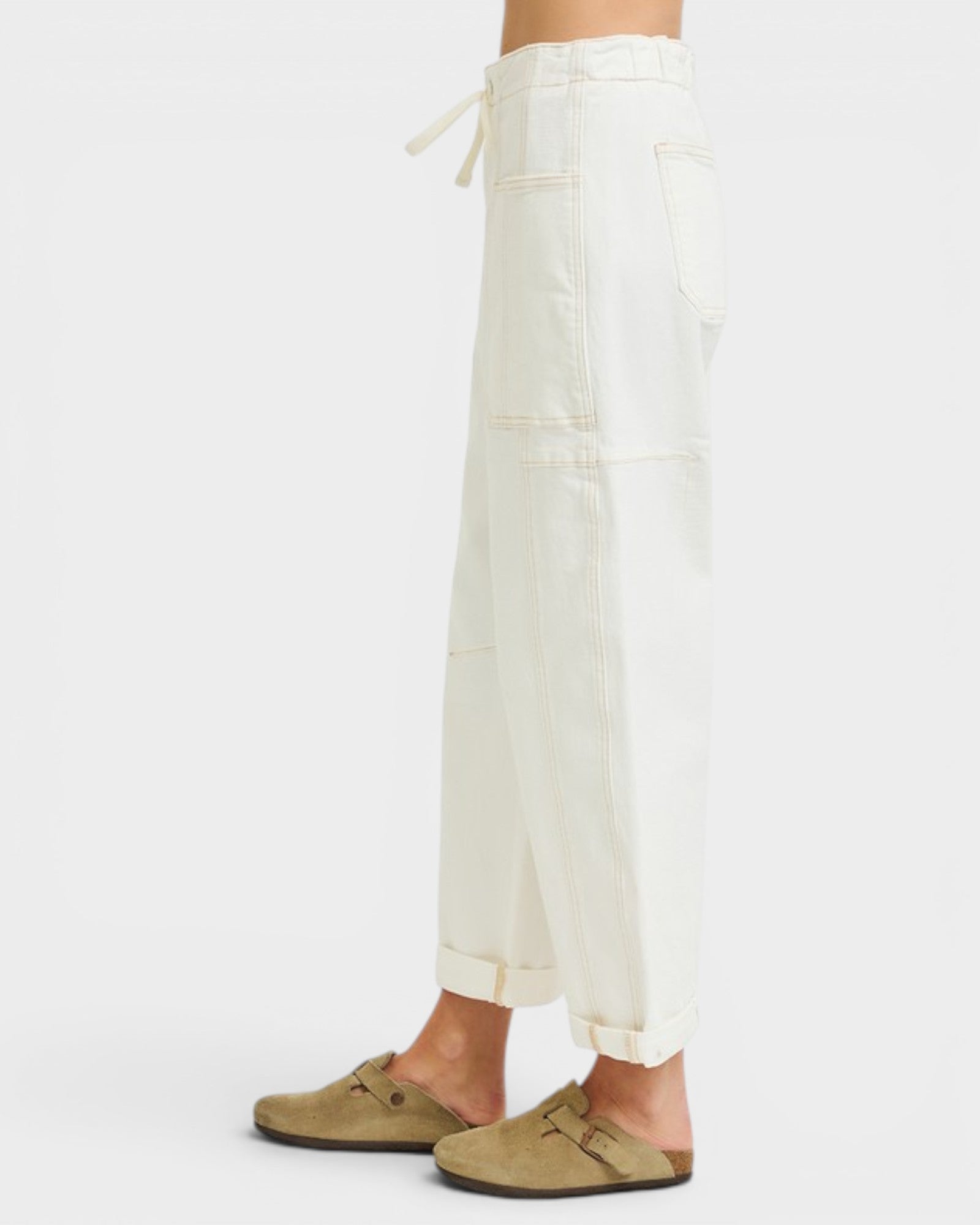 Person wearing white pants and brown shoes on a white background