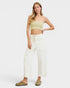 Woman wearing a light green crop top and white pants on a white background