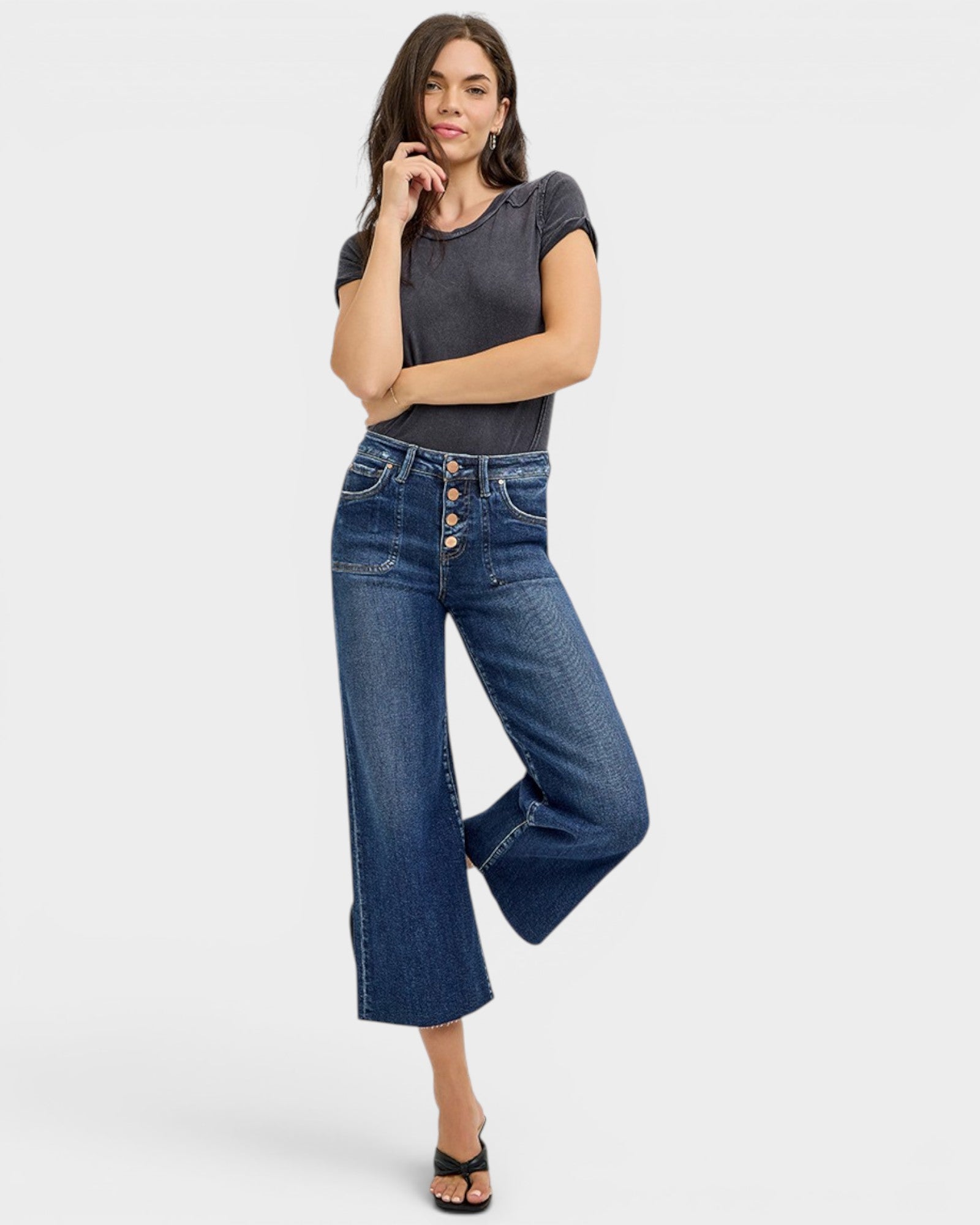 Woman wearing blue jeans and a dark gray top on a white background